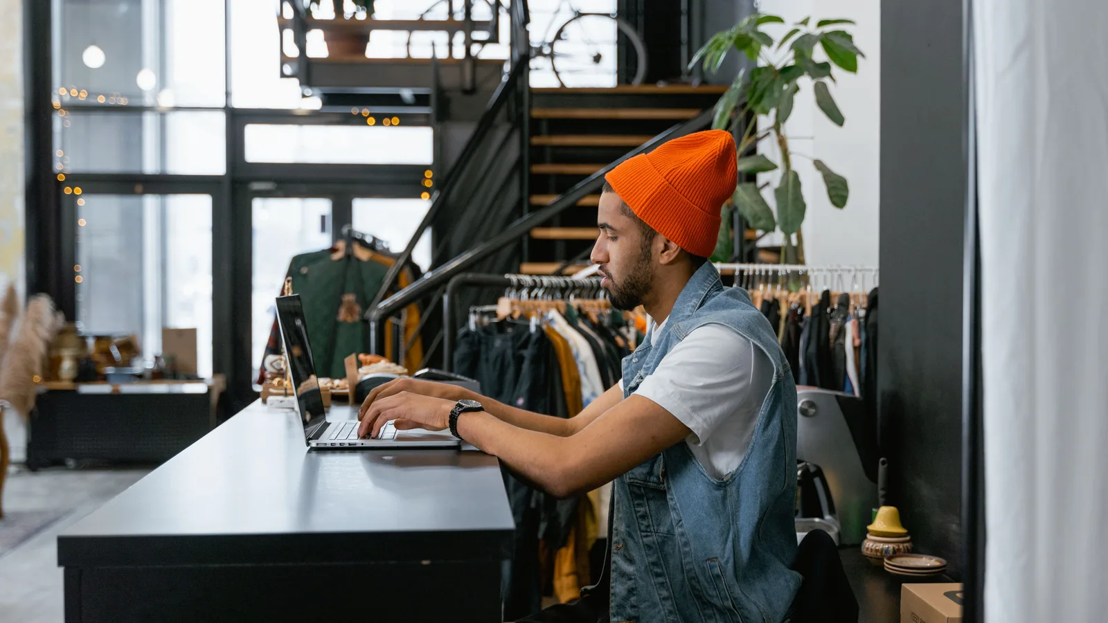Clothing store owner preparing customer information on a laptop behind the counter